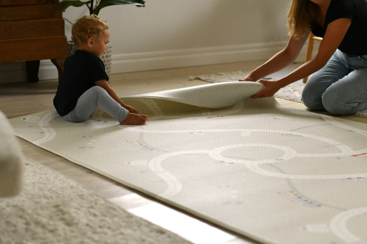 Lilleby lekmatta med mamma och barn som rullar kanten av lekmattan i skum.