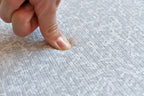 Finger trycker på premiumlekmatta med blåblommigt sommarängsmönster och fiskbensmönstrad baksida. 13 mm skum, EN71-godkänd.